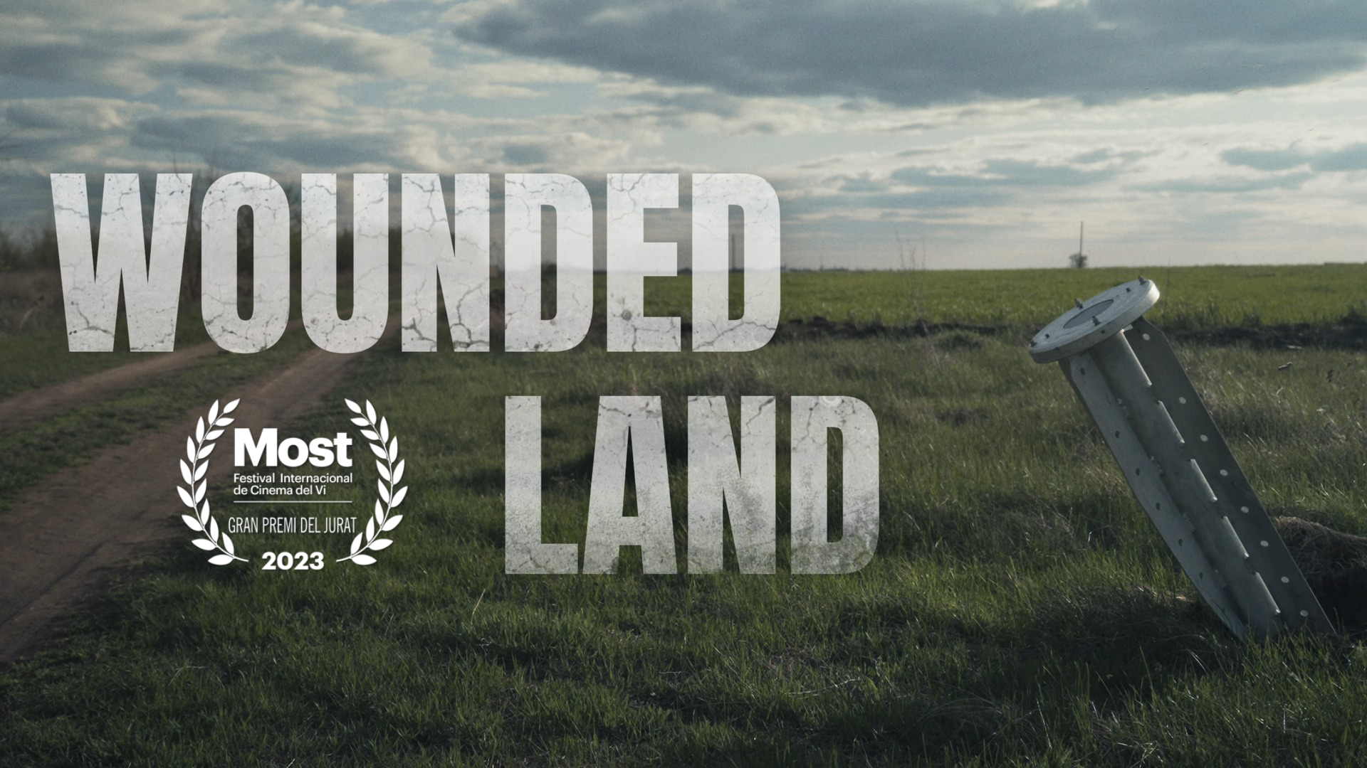 Wounded Land film banner with the Most film festival 2023 selection laurel over a rural landscape.